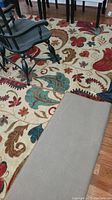 Two of the matching 5'x8' floral and paisley patterned area rugs on hardwood floor with furniture partially visible.