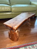 Full view of the driftwood bench showing the polished wood seat and sturdy legs.