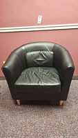 Front view of black leather armchair showing wooden legs and single cushion with slight imperfection