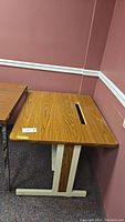 Photo of L & D wood veneer and metal dot matrix table, showing wood grain finish top with a rectangular slot and metal legs with wood vinyl panels. Table shows scratches from use.