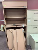 Front view of beige Storwal horizontal filing cabinet with six drawers removed and stacked inside the cabinet. Drawer fronts placed in front of cabinet.