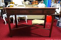 Side view of the vintage wooden desk showing three drawers, cross-braced legs, and wood finish.