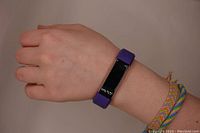 Purple Fitbit worn on wrist, showing device size and band color.