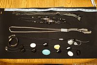Top view of five necklaces laid on a black surface for display, showing styles and lengths