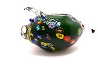 Side view of green glass pig piggy bank showing colorful millefiori patterns and clear glass ear and snout.