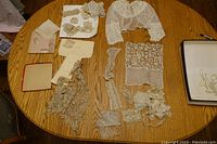 Wide view of assorted vintage lace pieces displayed on a wooden table including collars, trims, and fabric pieces