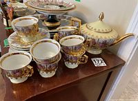 Teapot and eight cups with saucers arranged on wood surface