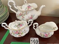 Photo of teapot, sugar bowl and creamer showing floral Moss Rose pattern with pink roses, gold trim and curved handles