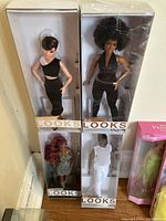 Four Barbie Signature Looks dolls displayed in boxes with two dolls standing stacked above the other two dolls.