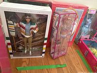 Wide view showing the boxed HBC Stripes Barbie, Soda Fountain Sweetheart Barbie in red Coca-Cola themed box, and After the Walk Barbie with red boxed background.