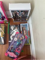 Five Barbie dolls in various themed original packaging grouped on floor corner