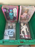 Four collector Barbie dolls in original packaging placed in a green bin, as seen from above.