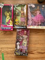 Four Barbie dolls boxed: Superstar Christie Barbie in yellow, Looney Tunes Barbie Tweety in yellow and pink, Nutcracker Barbie in pink dress, and Looney Tunes Barbie Bugs Bunny in patterned dress with figure.