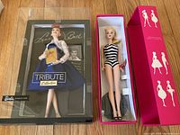 Front view of Lucille Ball Tribute Barbie and classic bathing suit Barbie in boxes on wood floor