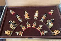 Top-down view of maroon felt-lined box containing hand-painted ceramic chess pieces