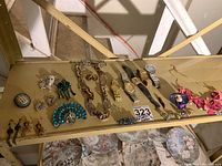 Wide angle showing all jewelry items including brooches, chains, earrings, and watches on a table.