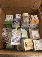 Top-down view of open cardboard box filled with multiple Lenox Spice Village porcelain house-shaped spice jars