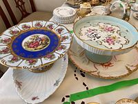 Overview of lot showing cobalt blue romantic scene stand and pale green floral stand on table