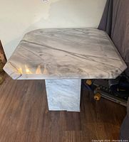 Full view of the square marble table showing octagonal-cut corners and marble veining pattern.