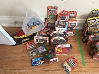 Collection of Matchbox model cars and packaging arranged on a wooden floor including loose cars and boxed models.