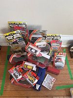 Overall view of the collection of Matchbox model cars stacked on a floor with some in original packaging.