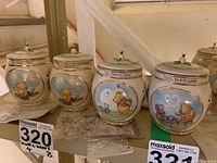 Photo of all four Winnie the Pooh honey pot music boxes showing front illustrations and overall design with gold accents and bee figurines on lids.