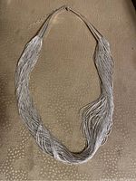 Full view of the sterling silver waterfall strand necklace laid flat on a surface.