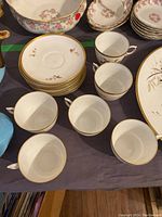View of six white porcelain teacups and stack of eight saucers among other pieces