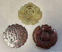 Photo showing three carved jade pendants of different colors and designs on a white background.