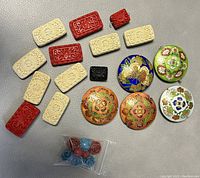 Overview of assorted Chinese beads showing round cloisonné enamel beads and rectangular carved beads in red, cream, and black colors; also small roses in plastic bag.