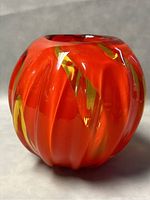 Close-up front angle of orange and amber blown glass vase showing swirling pattern and shape