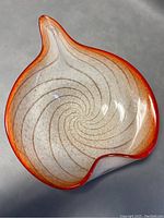 Top and angled views of the hand-blown glass bowl with vibrant red-orange rim and swirl pattern inside.