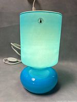 Blue glass mushroom lamp with light on showing translucent shade and original IKEA LYKTA sticker on shade