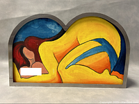 Front view of signed painting showing the nude figure in a unique arch-shaped metal frame.