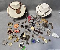 Full lot displayed on table showing assortment of necklaces, pins, brooches and bracelets.