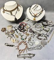 Overview of assorted vintage costume jewelry pieces displayed including necklaces, bracelets, brooches, pendants, and earrings in mixed metal finishes and styles.