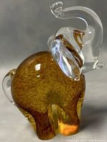 Close-up side view of amber blown glass elephant with clear ears and trunk showing iridescence and details.