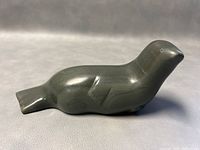 Side profile of the dark soapstone carved seal sculpture showing the artist's signature etched on the side.