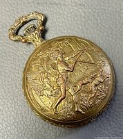 Close-up of the front embossed door showing a man playing a violin with dogs and a woman figure in background on gold-tone hunter case