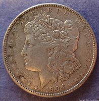 Obverse side of 1904 Morgan silver dollar showing Lady Liberty profile with date and text around edge.