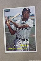 Front color image of Larry Doby in Chicago White Sox uniform holding a bat in batting stance on a baseball field.