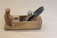 Full length photo of wooden smoothing plane showing wooden body, handle, and metal blade assembly.