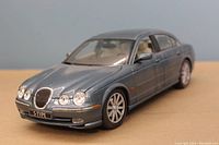 Front angle image showing the detailed front grille, headlights, hood and wheels of the 1999 Jaguar S Type Sedan model in metallic blue-grey color.