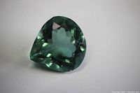 Close-up photo of heart-shaped green tourmaline gem showing facets and depth of cut.