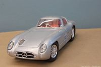 Front three-quarter view showing silver metal body, Mercedes emblem on grille, clear headlights, and red interior.