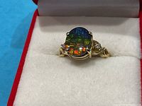 Front close-up showing central opal cabochon with red, green and blue flashes and flanking diamonds