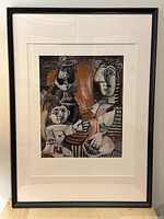 Full view of framed Picasso print 'The Family' showing the entire artwork within the black frame and white matting over a light wood surface.