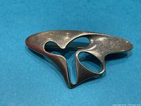 Front view of brooch showing abstract amoeba-like cutout design on blue background