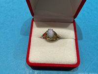 Ring displayed in red velvet box showing front view of opal and band