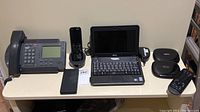 Photo showing an office phone, cordless phone, and Dell laptop on a desk